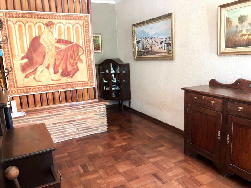 A living area featuring classic parquet timber flooring and a decorative brick-based timber slat room divider, offering a traditional aesthetic.