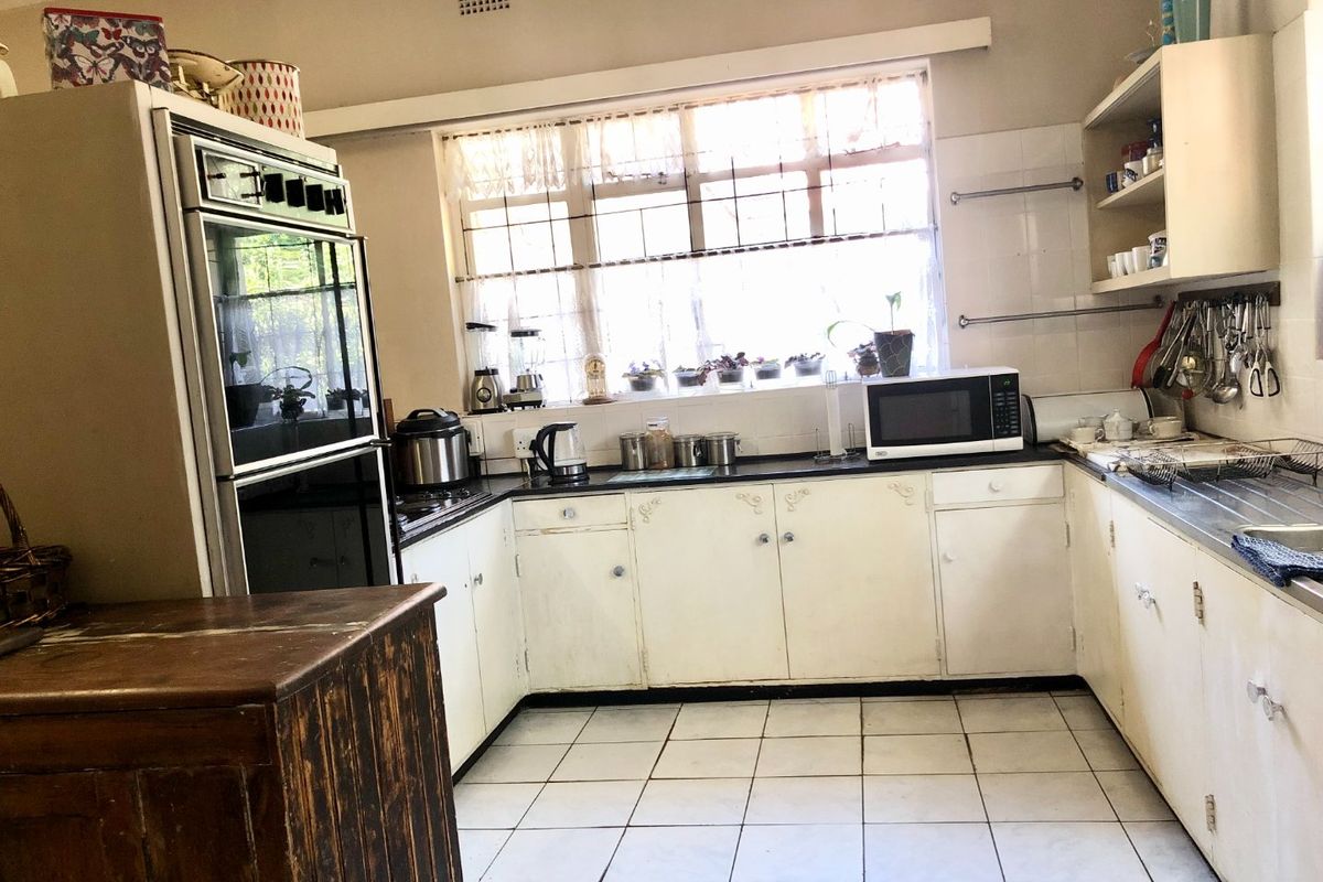 A dated kitchen featuring built-in cabinetry, a double sink, and a built-in oven, offering significant potential for modernization and renovation.
