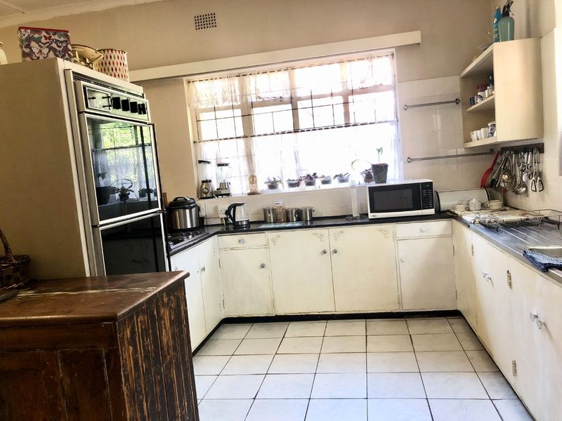 A dated kitchen featuring built-in cabinetry, a double sink, and a built-in oven, offering significant potential for modernization and renovation.