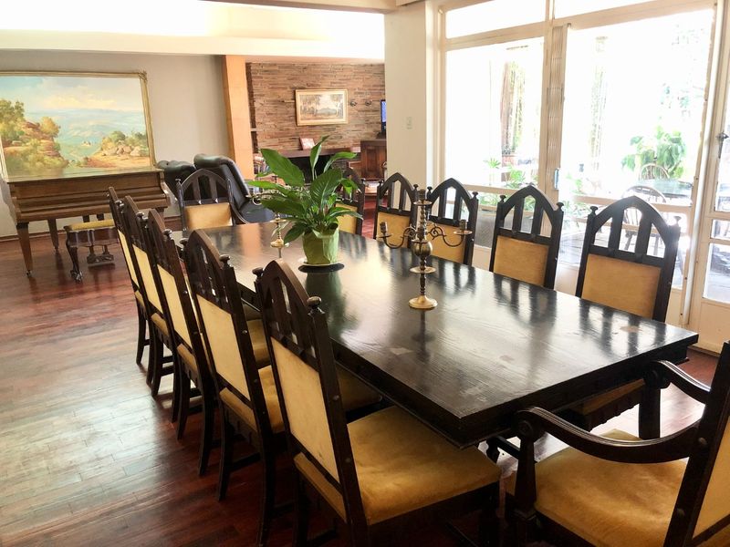 Spacious dining area featuring rich hardwood flooring, a brick feature wall, and large glass sliding doors providing ample natural light.