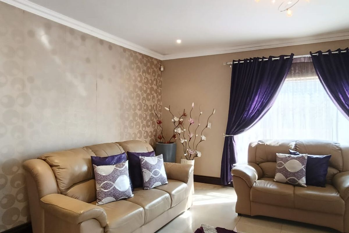 A comfortable living room featuring a stone-clad fireplace, tiled flooring, and decorative wallpaper, offering a warm and inviting space for relaxation.