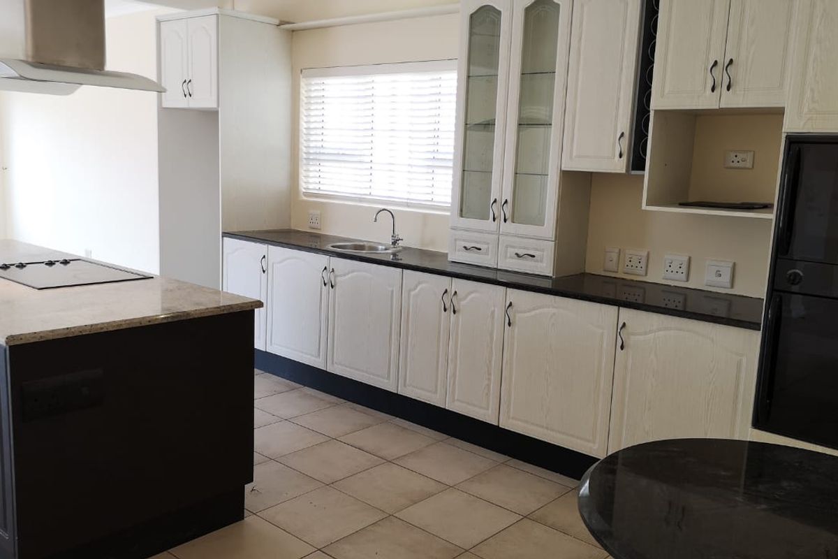 Spacious kitchen featuring a large island, granite countertops, built-in oven, extractor fan, and ample cabinetry, offering a functional layout for cooking and entertaining.