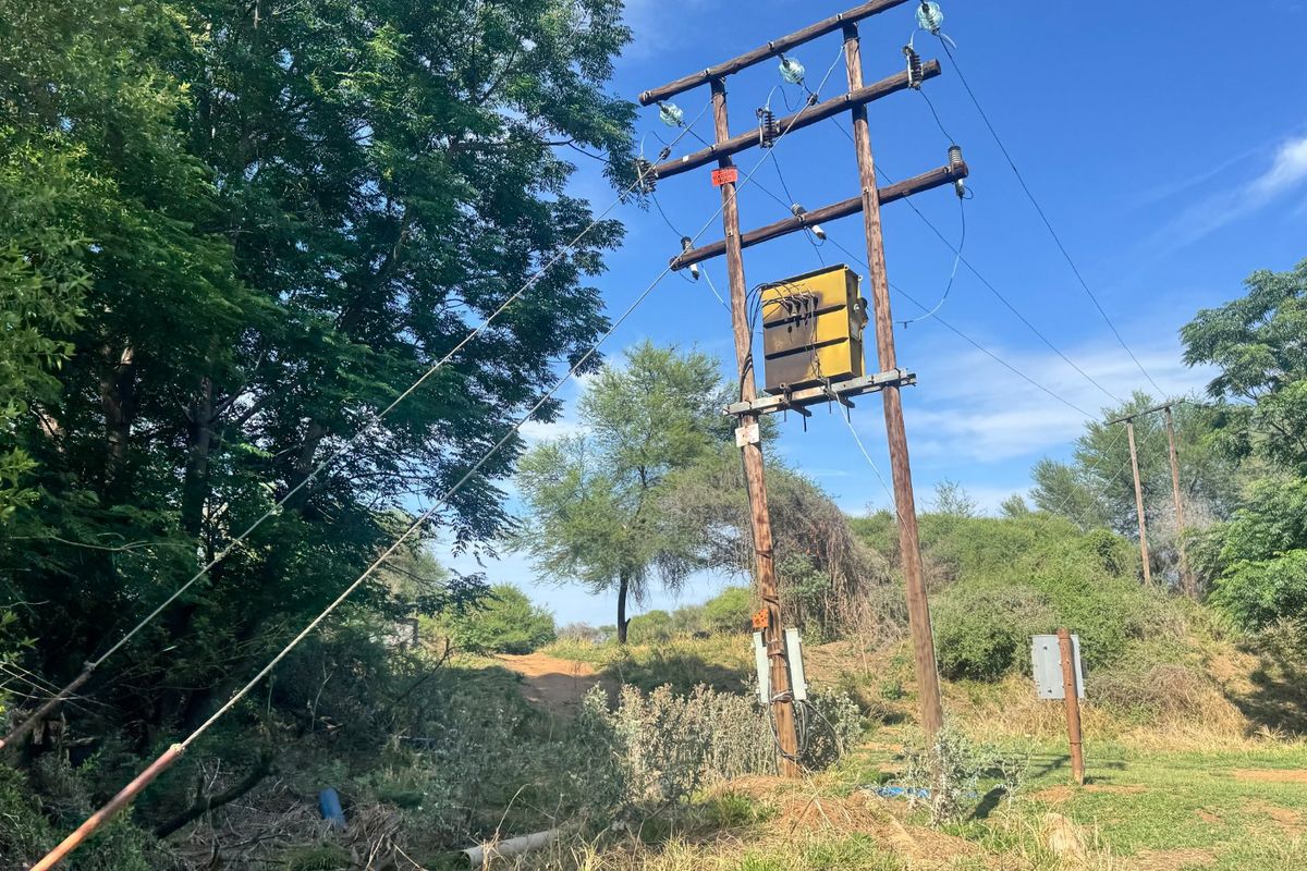An outdoor view of a utility pole featuring an electrical transformer and overhead power lines situated on the farm property.