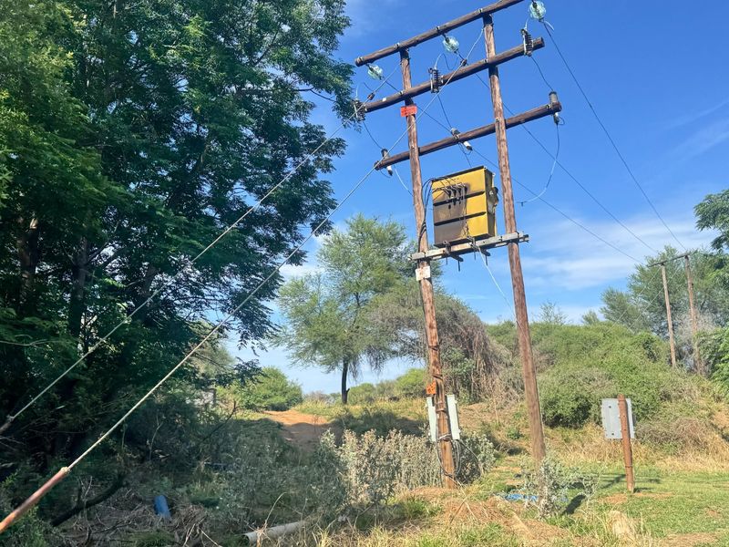 An outdoor view of a utility pole featuring an electrical transformer and overhead power lines situated on the farm property.