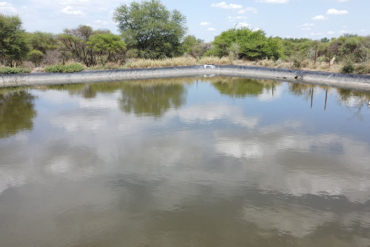 A large lined farm reservoir or dam situated in a natural landscape setting, used for water storage on the property.