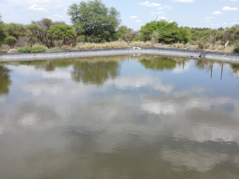A large lined farm reservoir or dam situated in a natural landscape setting, used for water storage on the property.