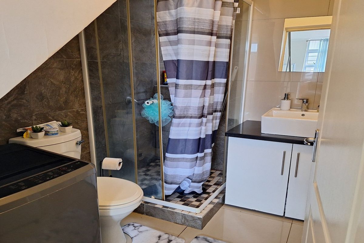 Compact bathroom featuring a shower enclosure, modern vessel sink with vanity storage, and tiled finishes throughout.