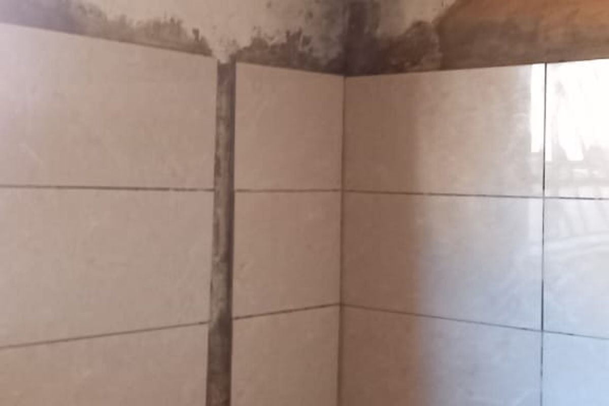 A bathroom featuring a built-in bathtub with wall tiling, requiring significant repairs to the plaster and ceiling finishes.