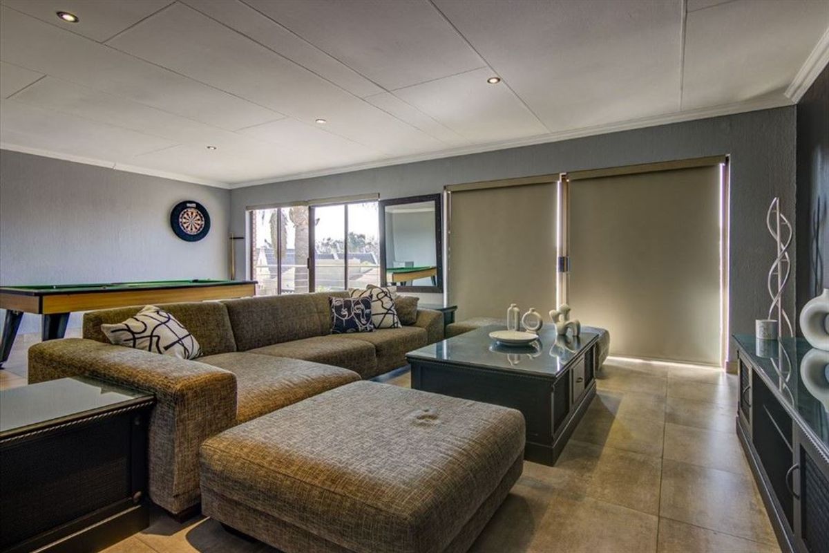 Spacious living room featuring large format floor tiles, recessed ceiling lighting, and sliding glass doors with roller blinds providing access to the exterior.
