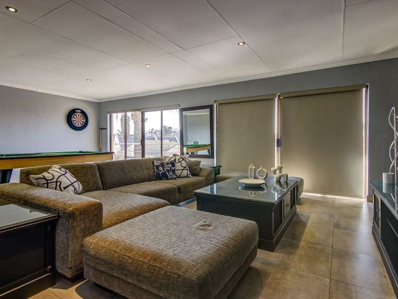 Spacious living room featuring large format floor tiles, recessed ceiling lighting, and sliding glass doors with roller blinds providing access to the exterior.