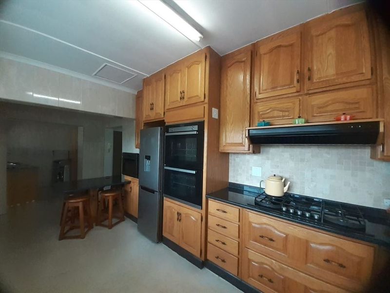 A functional kitchen featuring traditional wooden cabinetry, granite countertops, a built-in double oven, and a gas hob with an extractor fan.
