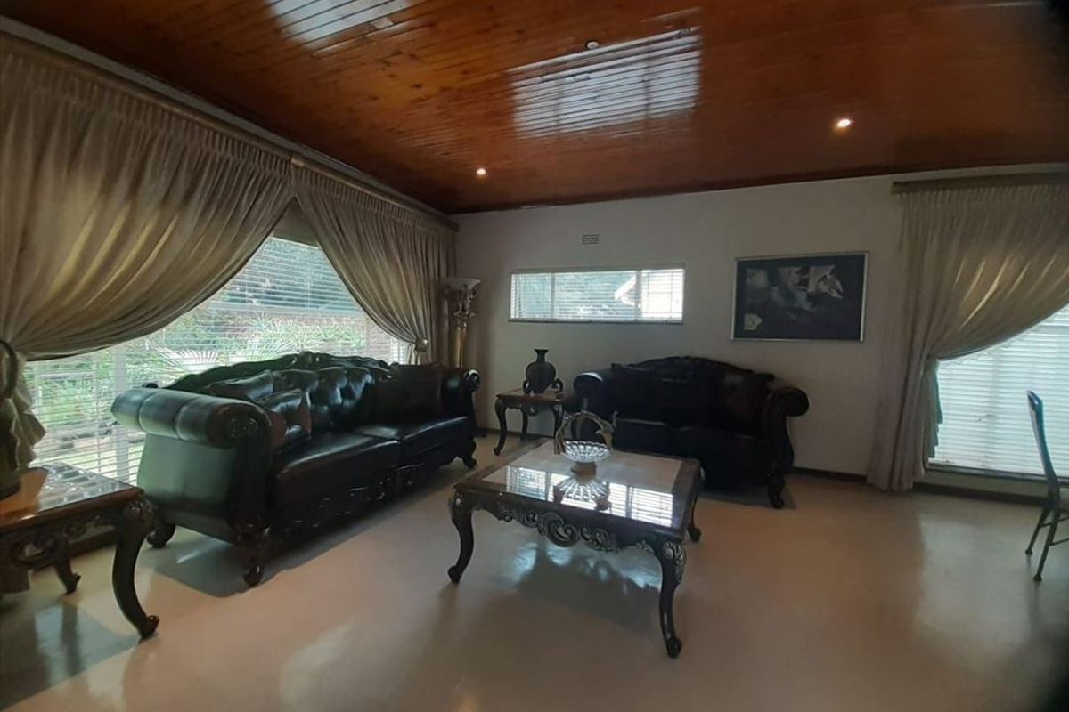 Spacious living room featuring a warm timber tongue and groove ceiling, recessed downlighting, and large windows allowing for ample natural light.