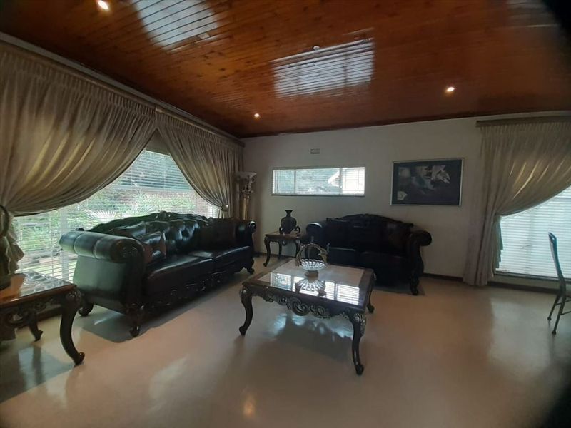 Spacious living room featuring a warm timber tongue and groove ceiling, recessed downlighting, and large windows allowing for ample natural light.