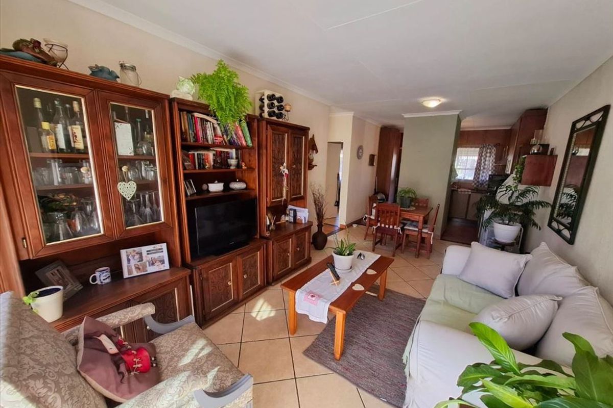 Open-plan living and dining area featuring ceramic floor tiles and a connected kitchen space with traditional cabinetry.