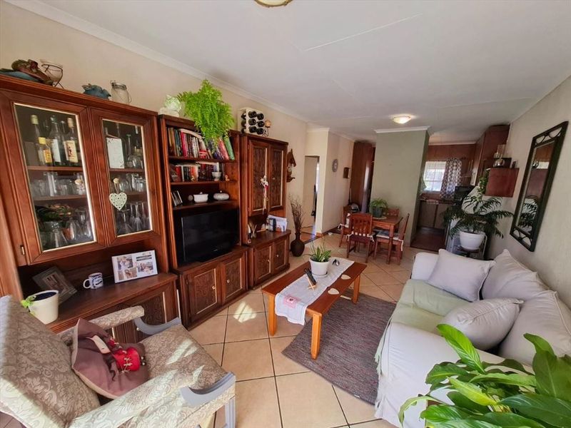 Open-plan living and dining area featuring ceramic floor tiles and a connected kitchen space with traditional cabinetry.