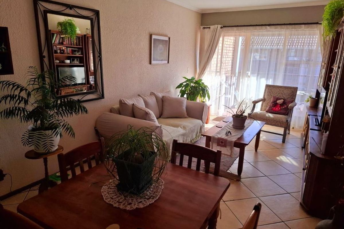 A living room area featuring tiled flooring and a large sliding glass door that provides natural light and access to the exterior.