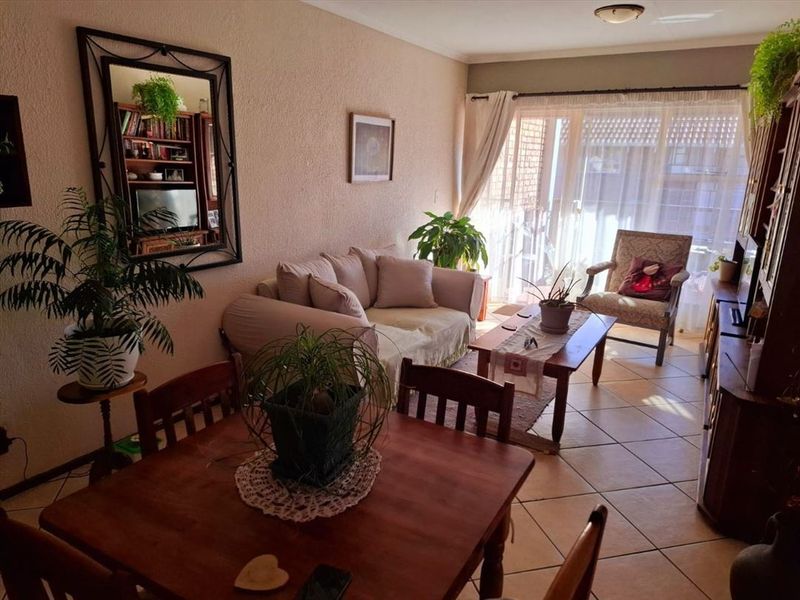 A living room area featuring tiled flooring and a large sliding glass door that provides natural light and access to the exterior.