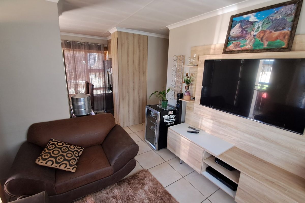 A comfortable living room featuring a modern built-in media unit, neutral tiled flooring, and coved ceiling details.