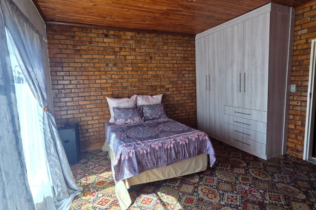 Bedroom featuring exposed brick walls, a timber ceiling, and a built-in wardrobe, offering a rustic aesthetic with potential for modern updates.