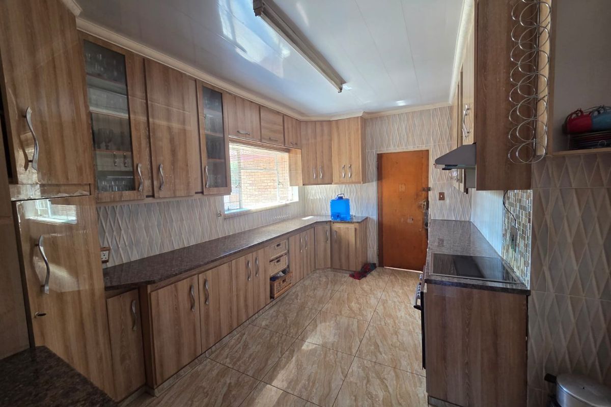A functional kitchen featuring extensive wood-look cabinetry, granite countertops, tiled backsplash, and integrated appliances, offering a practical layout for daily meal preparation.