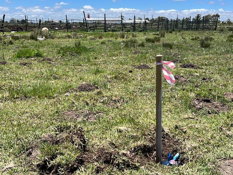 A view of the vacant residential land featuring a survey marker stake and perimeter fencing.