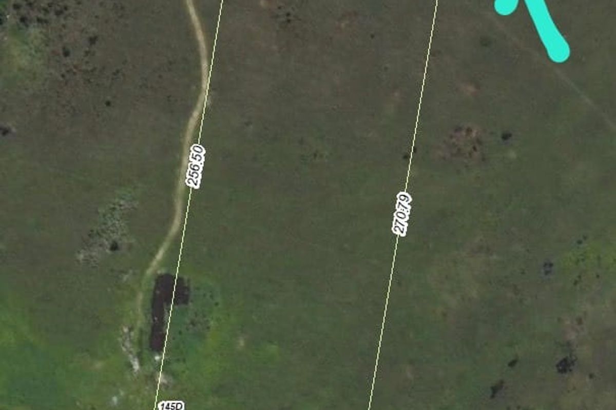 Aerial view of a vacant residential plot showing boundary dimensions and access road.