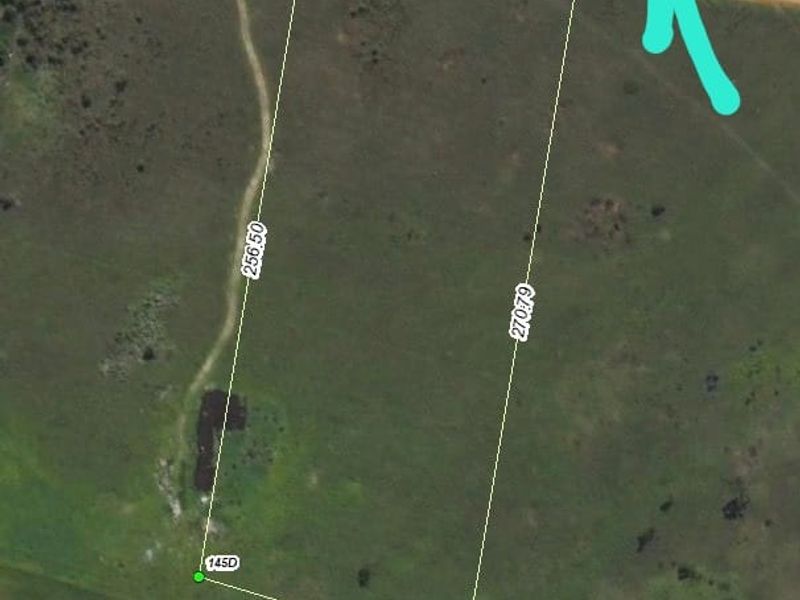 Aerial view of a vacant residential plot showing boundary dimensions and access road.