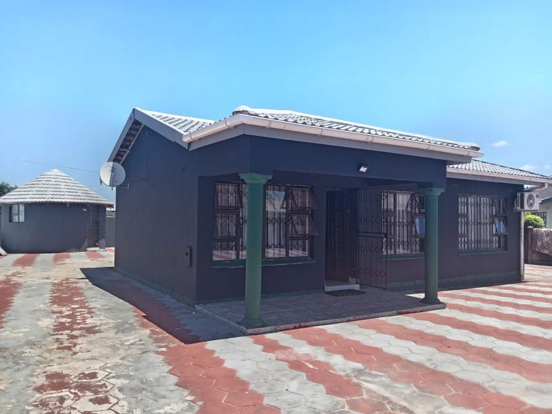Front view of a single-story house featuring a covered patio, security bars on windows, and a paved driveway.