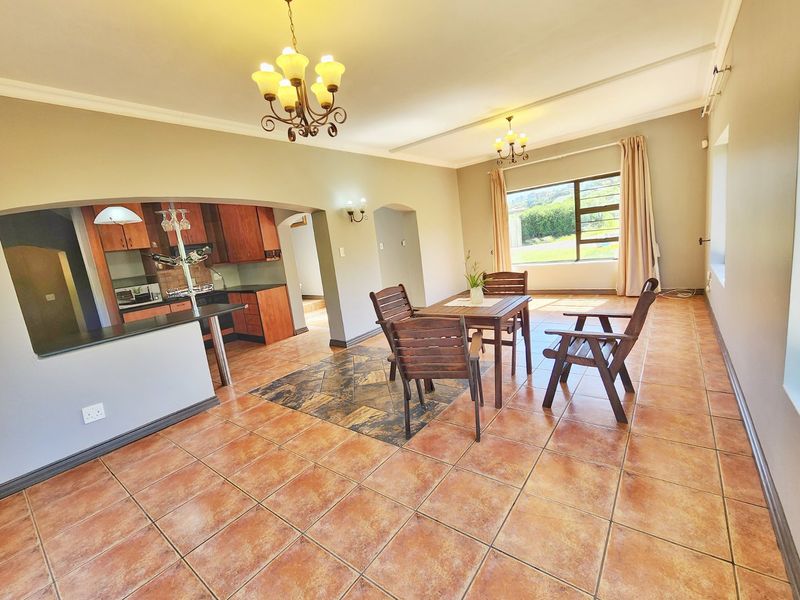 Spacious open-plan living and dining area featuring tiled floors, an arched transition to the kitchen, and a breakfast bar with granite countertops.