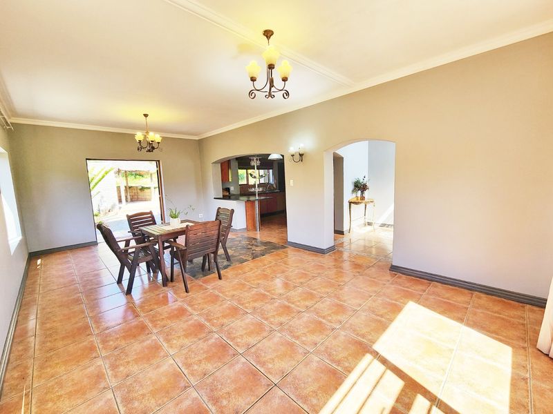 Spacious open-plan living and dining area featuring ceramic tile flooring, arched transitions, and direct access to the outdoor patio.