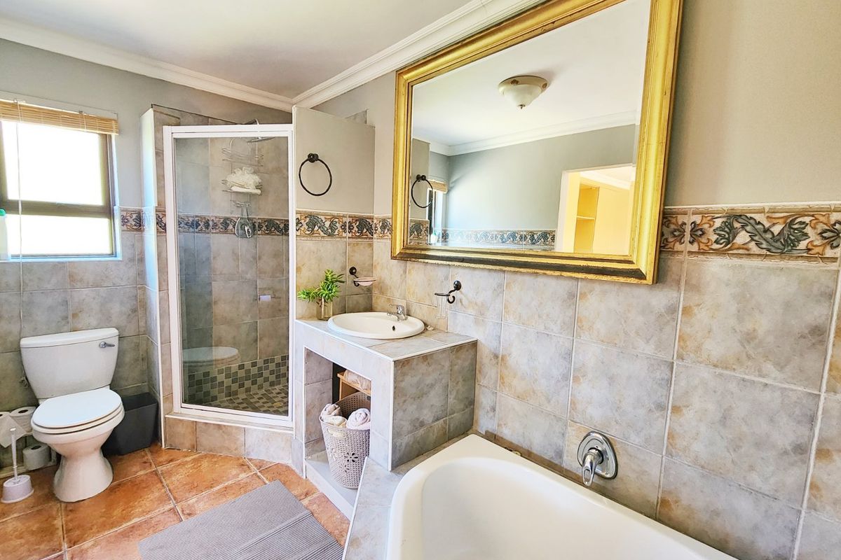 A functional bathroom featuring a tiled shower enclosure, built-in vanity with basin, bathtub, and classic wall tiling throughout.