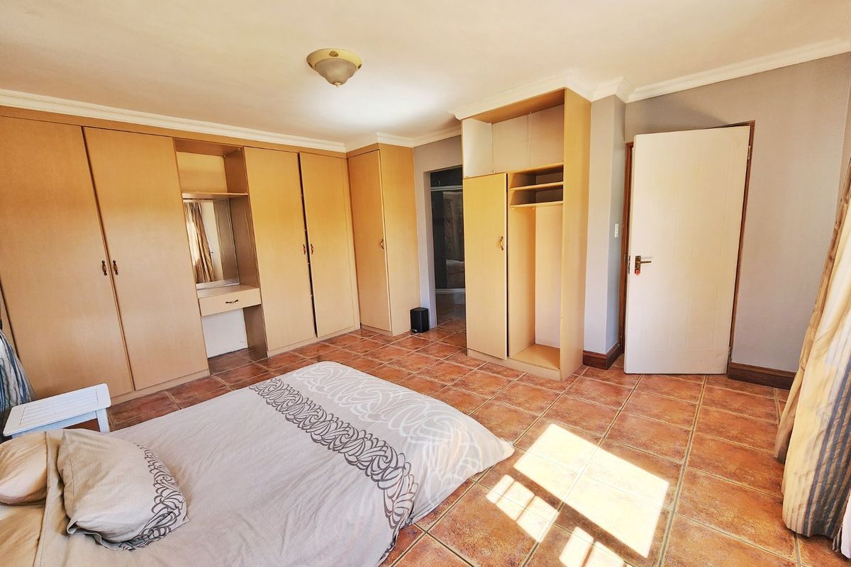 A bedroom featuring extensive built-in wooden cabinetry, tiled flooring, and coving, offering ample storage space and a functional layout.