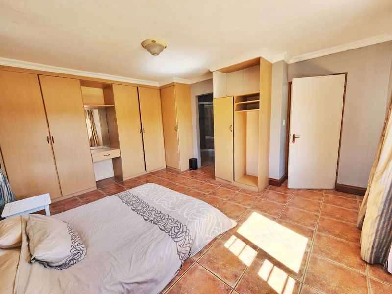 A bedroom featuring extensive built-in wooden cabinetry, tiled flooring, and coving, offering ample storage space and a functional layout.