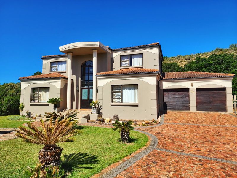 A well-maintained double-story residential home featuring a paved driveway, double garage, and an elegant arched entrance with decorative columns.