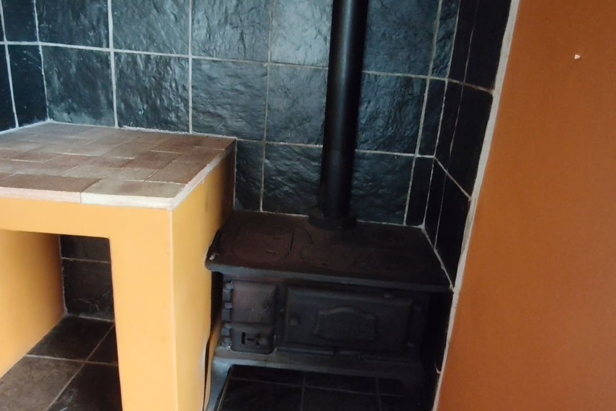 A corner feature area featuring a cast iron wood burning stove with a tiled splashback and built-in masonry counter.