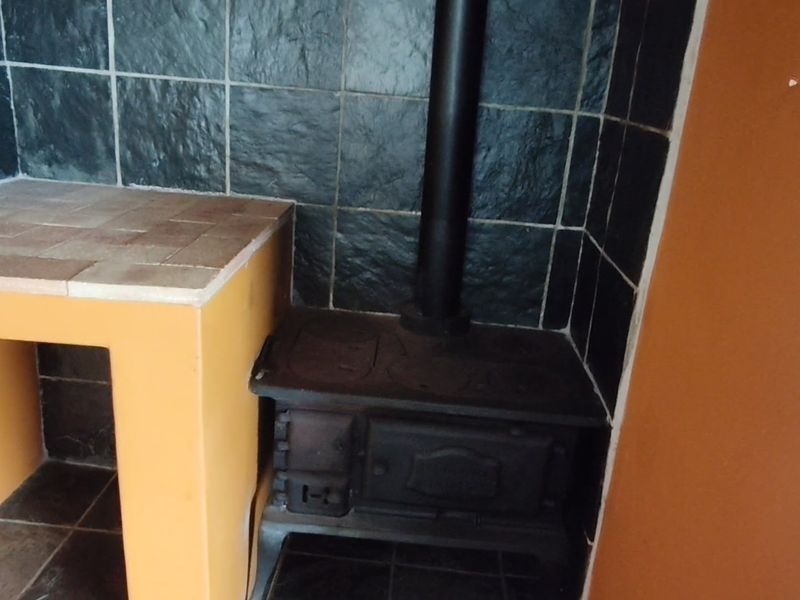 A corner feature area featuring a cast iron wood burning stove with a tiled splashback and built-in masonry counter.