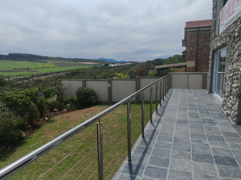 Spacious elevated balcony featuring slate tile flooring, a modern stainless steel balustrade, and expansive views over the surrounding landscape.