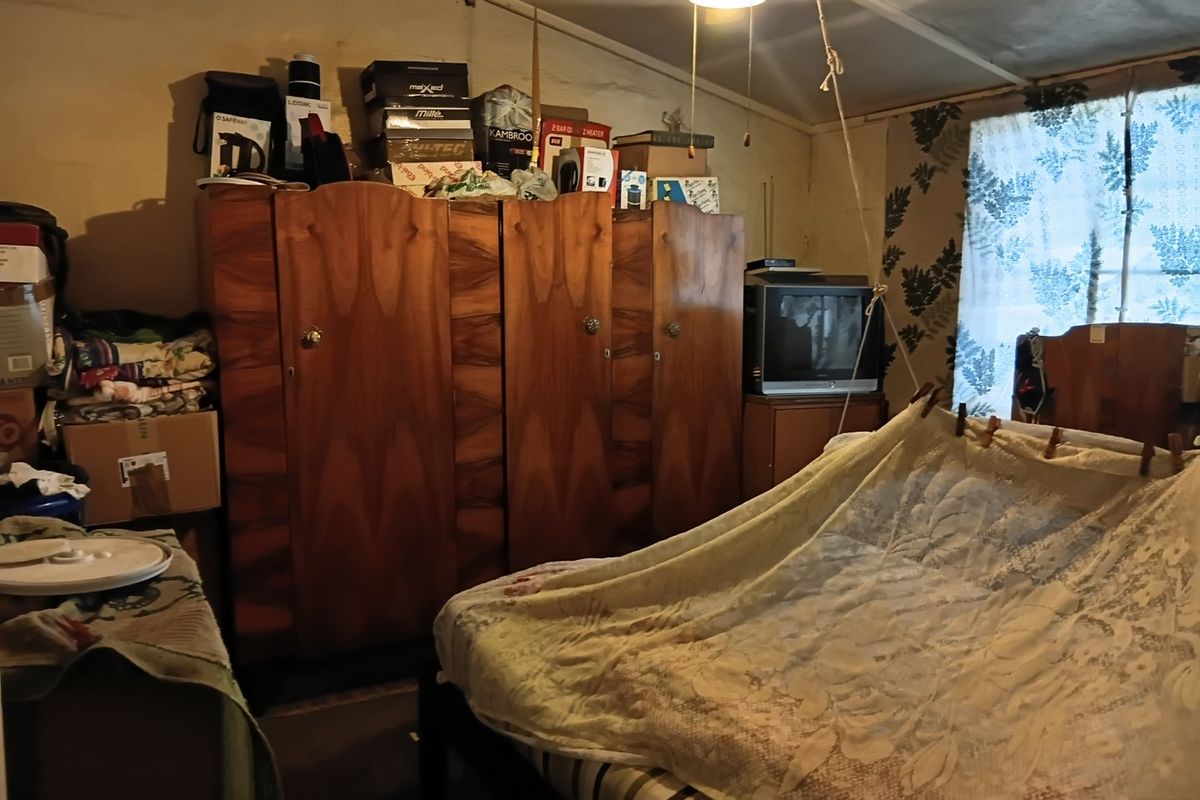 A bedroom featuring a ceiling fan and dated wall finishes, requiring cosmetic updates and repairs to improve the overall condition and appeal.