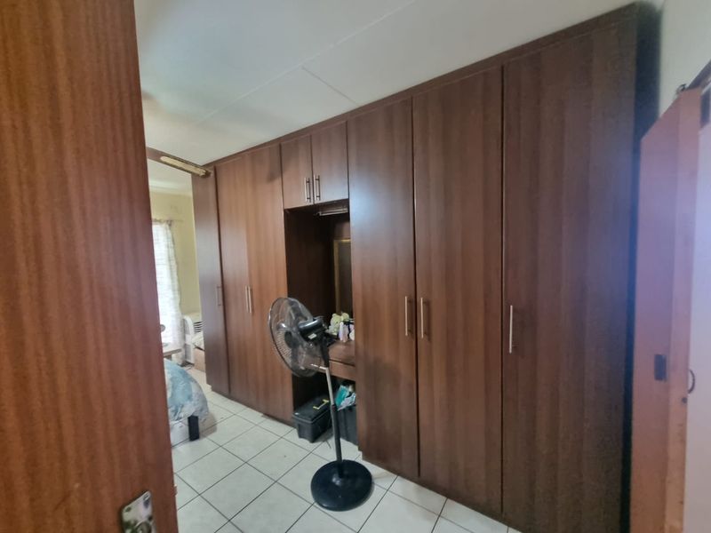 A bedroom featuring extensive dark wood built-in cupboards and tiled flooring, offering ample storage space.