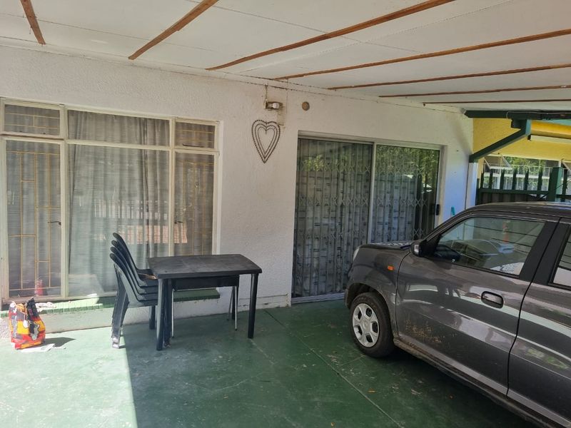 A covered patio area featuring sliding glass doors with security gates and painted concrete flooring, providing a functional outdoor transition space.