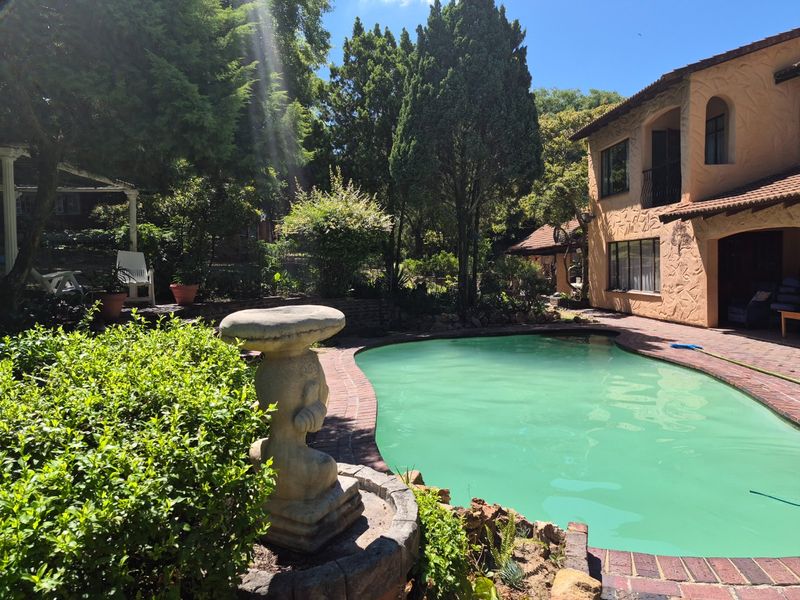 A private backyard pool area featuring brick paving, a stone bird bath, and a two-story home with a textured stucco exterior finish.