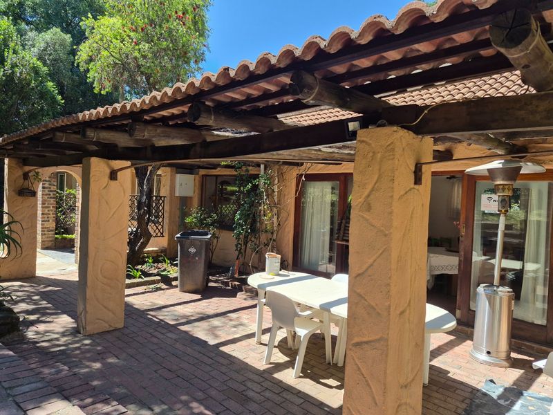 Covered outdoor patio area featuring a timber pergola, textured masonry columns, and brick paving, providing direct access to the interior living space.