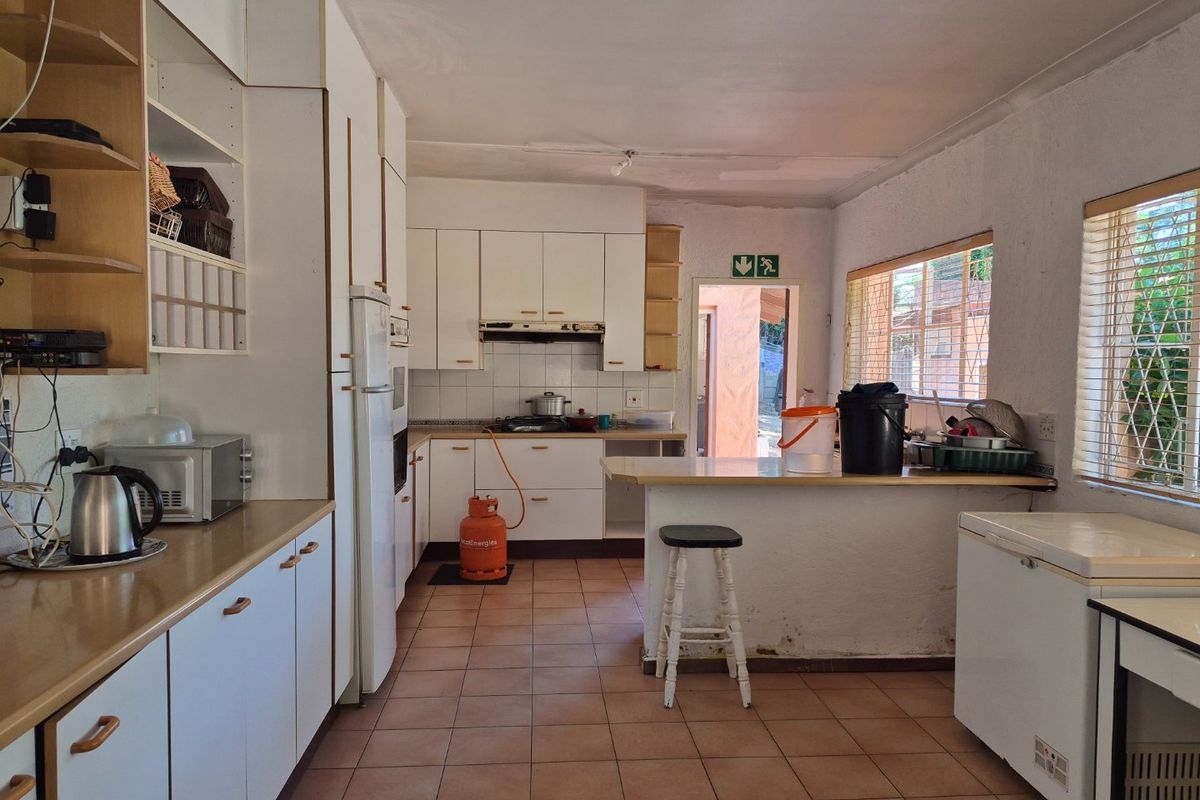 A functional kitchen featuring built-in cabinetry, a breakfast bar, and tiled flooring, offering potential for modernization and cosmetic updates.