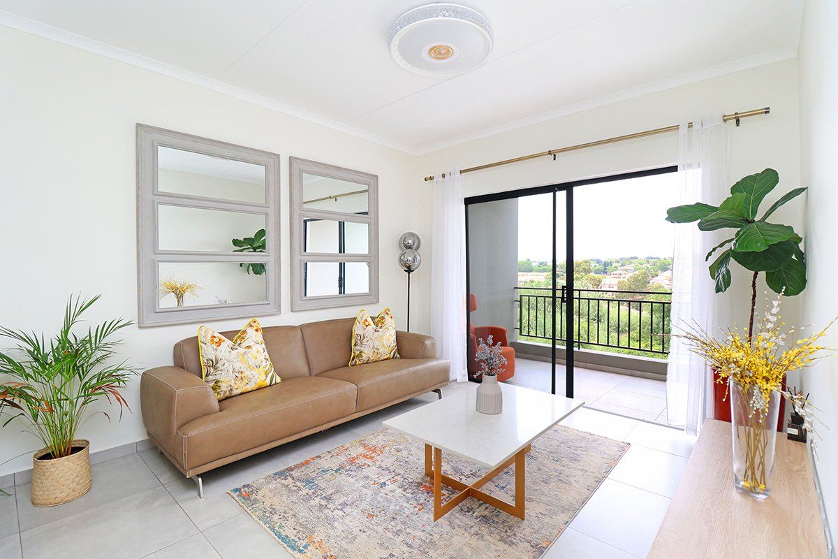 Bright living room featuring neutral tiled flooring, a modern ceiling light, and large sliding glass doors providing direct access to a private balcony.