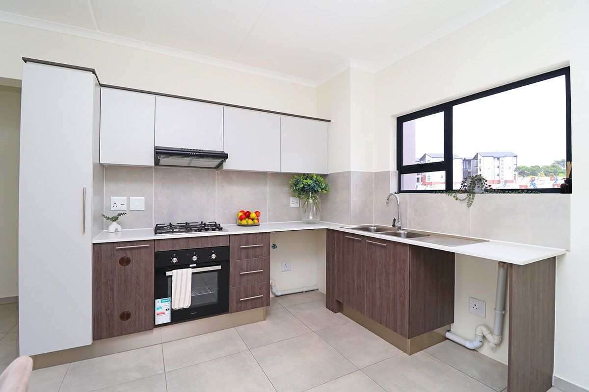 Modern kitchen featuring two-tone cabinetry, gas hob, built-in oven, extractor fan, and tiled splashback with ample counter space and plumbing for appliances.
