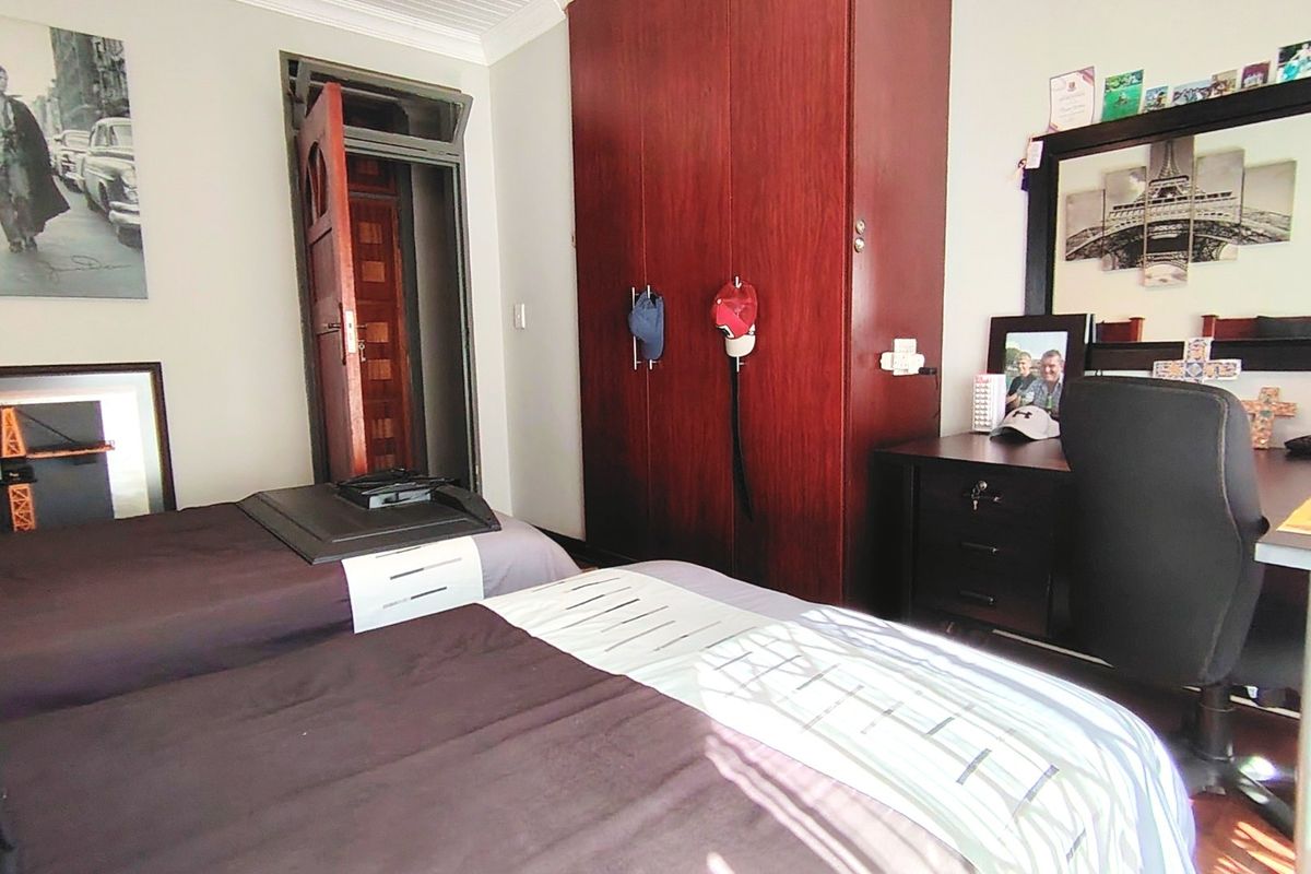 A functional bedroom featuring a built-in wooden wardrobe and a classic timber door, offering a practical layout with standard finishes.