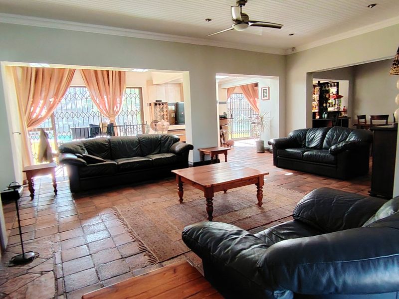 Spacious open-plan living area featuring terracotta tiled flooring, a central fireplace, and direct access to the outdoor patio through security gates.
