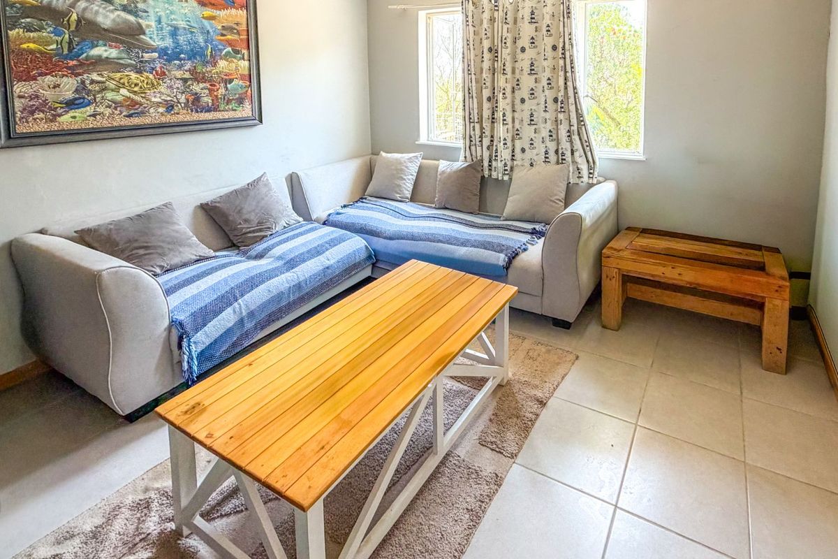 A living room featuring tiled flooring and natural light from a window, providing a functional space for relaxation.