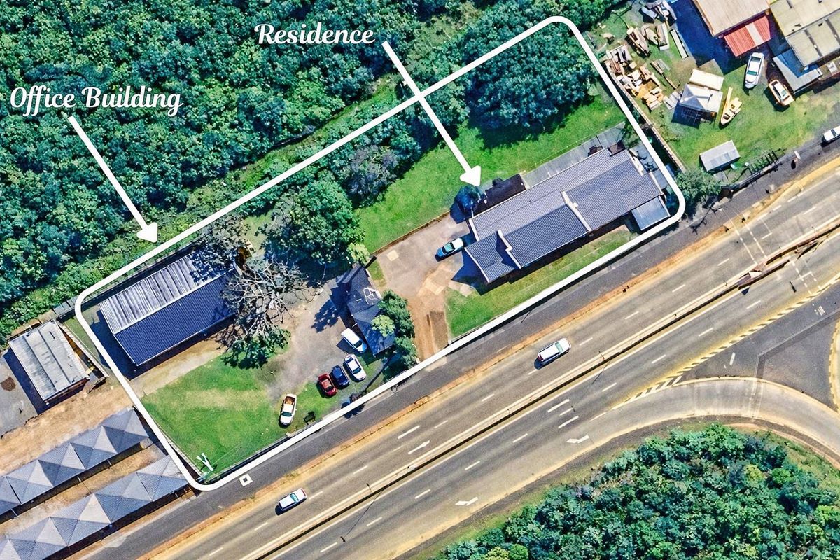 Aerial view of the property showing the residence and office building situated on a large plot with driveway access and surrounding greenery.