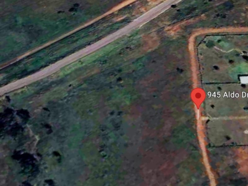 An aerial view of the vacant residential land plot located at 945 Aldo Dr, showing surrounding terrain and road access.